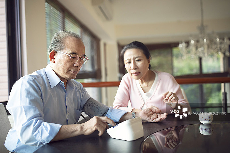 年长的亚洲夫妇使用血压计检查健康状况图片素材