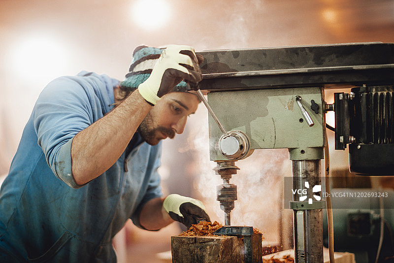 木匠在车间使用钻床在木头上钻孔图片素材