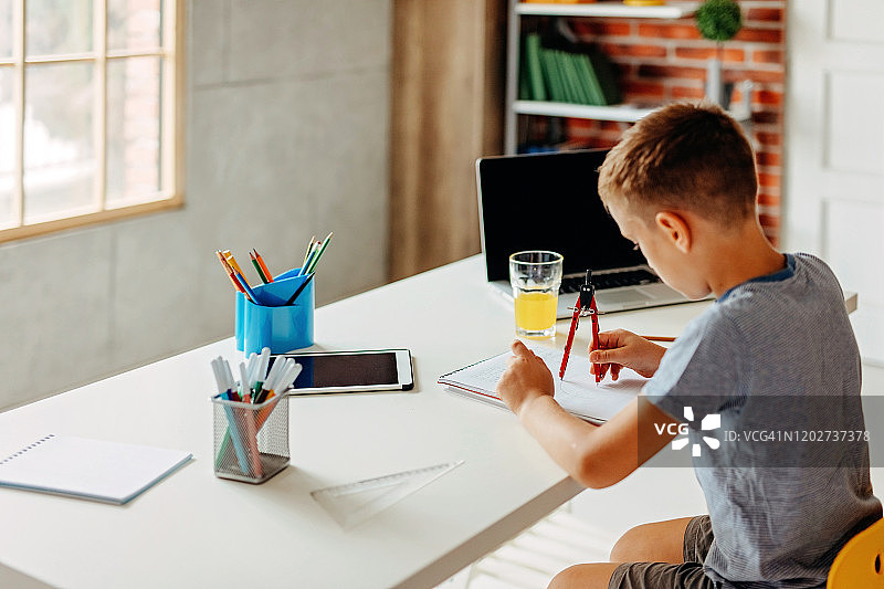 疲惫的男孩在家拿着书写字图片素材