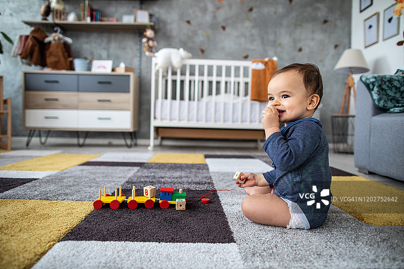 坐在地板上啃东西的快乐男宝宝图片素材
