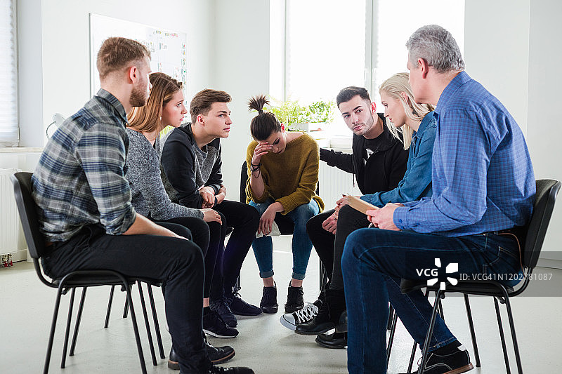 与朋友和治疗师坐在一起的情绪低落的女人图片素材