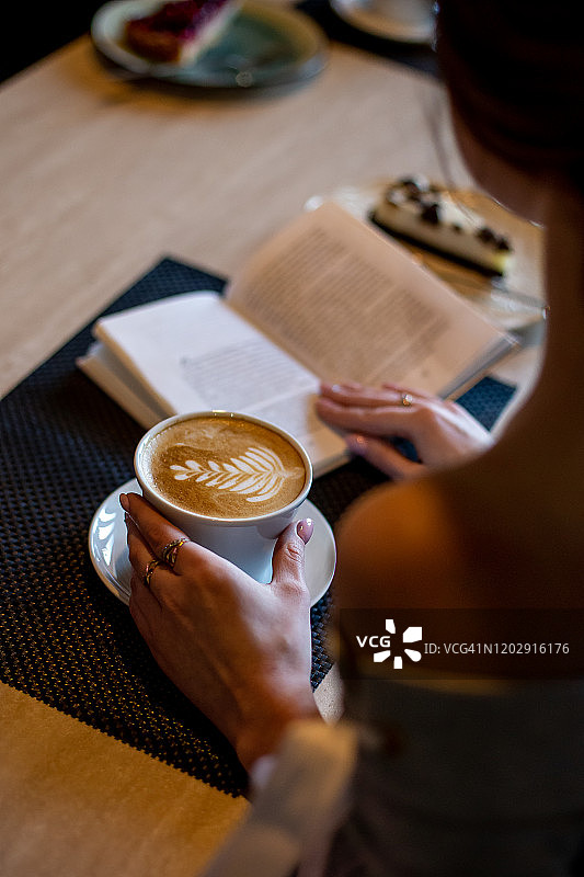 手捧咖啡杯和书本图片素材