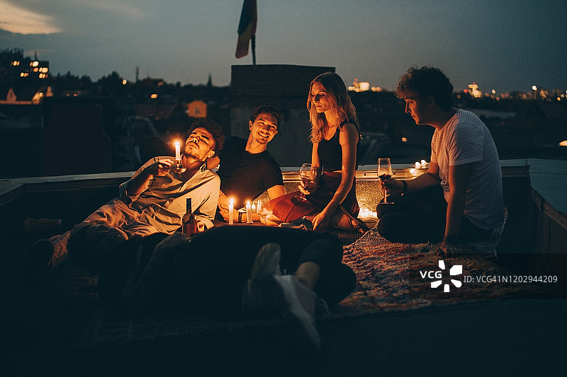 朋友们在黄昏时分于城市露台上点着蜡烛品酒放松图片素材