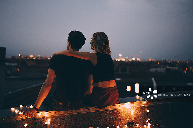 城市灯光露台上相拥而坐情侣的背影图片素材