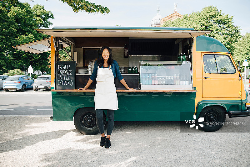 面带微笑的女老板站在餐车前的肖像照图片素材