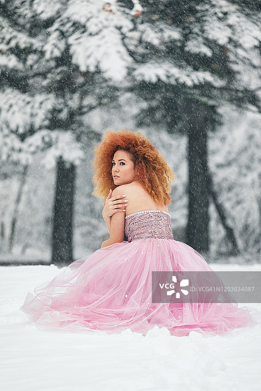 我的冬季童话：身穿华丽粉色连衣裙的美丽女孩在雪林中图片素材
