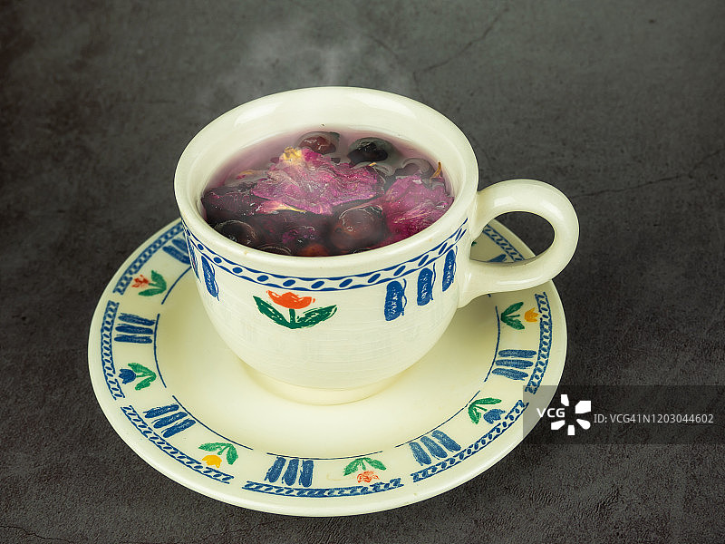 一杯含有药用草本、玫瑰果、山楂和玫瑰花瓣的热饮图片素材
