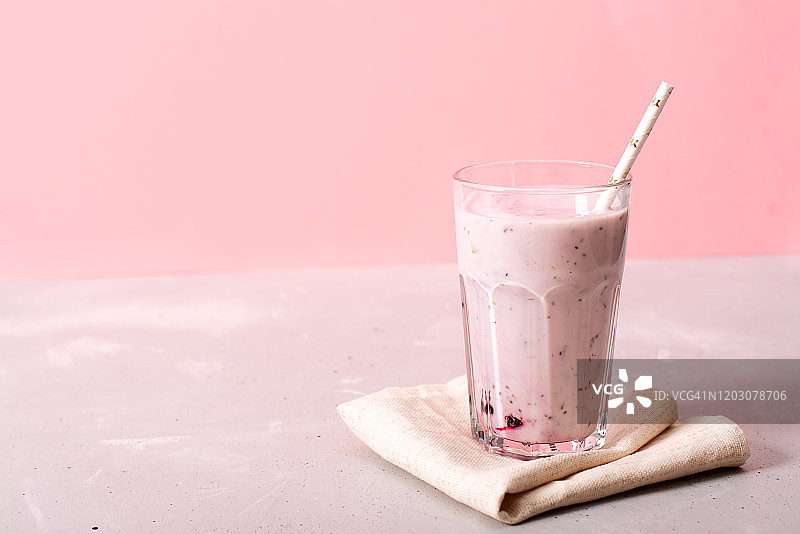 粉色背景上的两杯蓝莓冰沙。从搅拌机倒入玻璃杯中图片素材