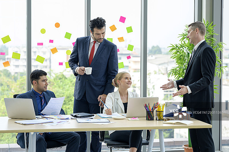 商务人士在办公室的会议上集思广益，分享想法，使用笔记本电脑和平板电脑记录想法、计划和项目图片素材