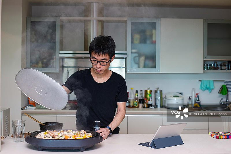 男人在互联网的帮助下在电热板上做饭图片素材