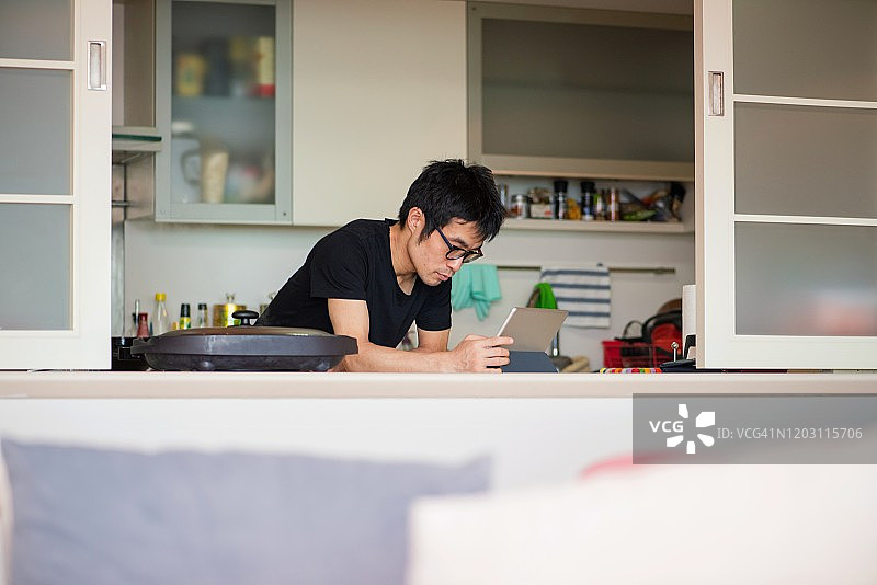 男人在互联网的帮助下在电热板上做饭图片素材