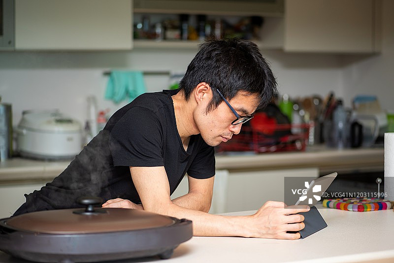 男人在互联网的帮助下在电热板上做饭图片素材