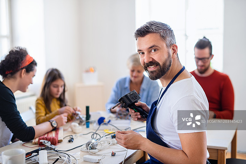 一群在社区中心修理家用设备的人。图片素材