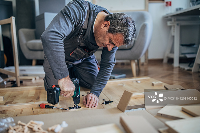 穿着工作服组装木制家具的木匠图片素材