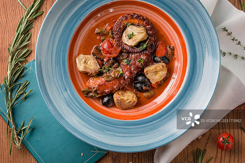 木桌上的章鱼触角海鲜橄榄番茄汤图片素材