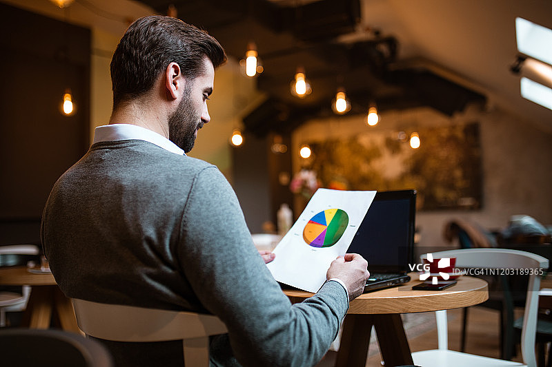 在咖啡馆分析饼图结果的商人图片素材