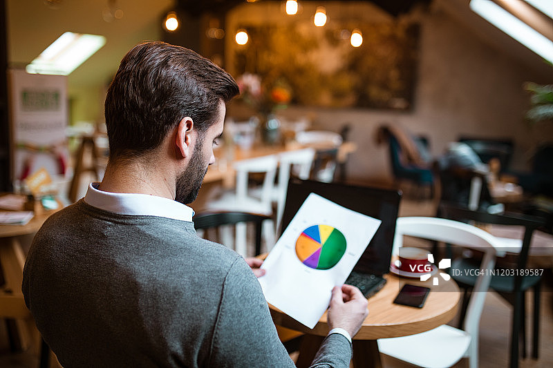 在咖啡馆分析饼图结果的商人图片素材