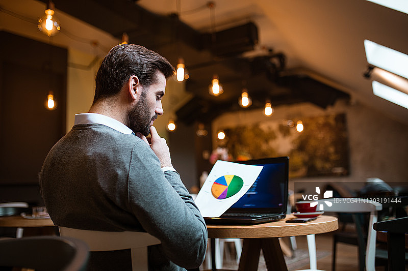 在咖啡馆分析饼图结果的商人图片素材