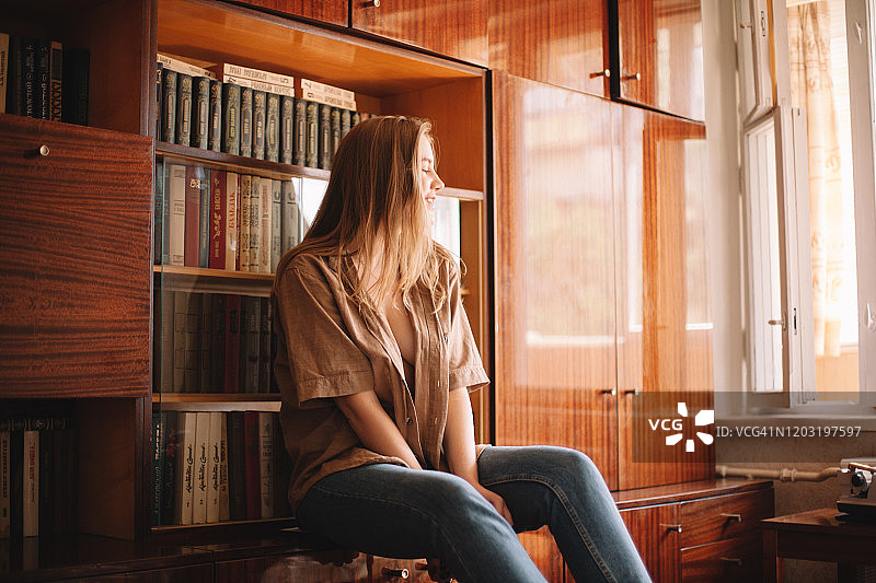坐在书架旁的年轻女人图片素材