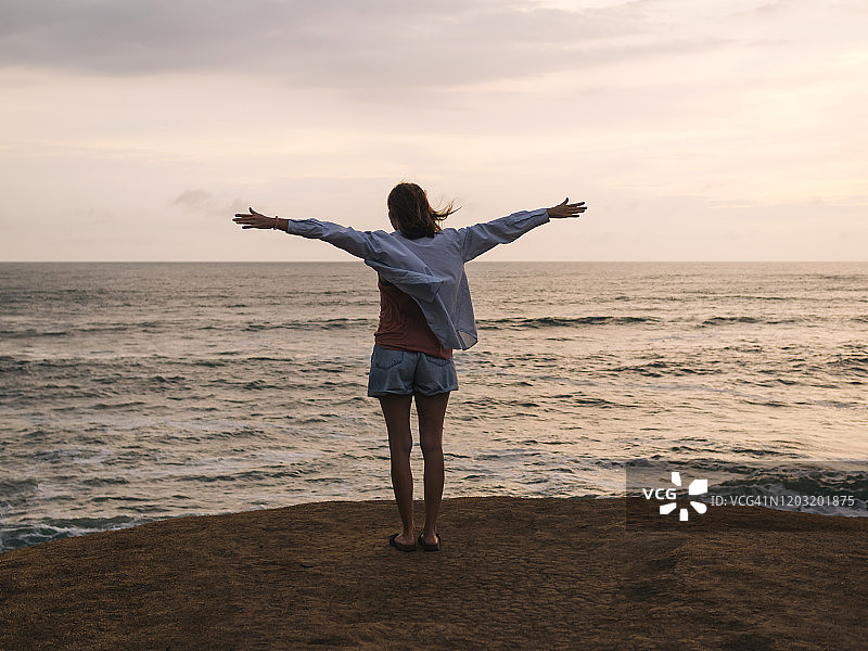 日落时分在海边张开双臂的女人图片素材