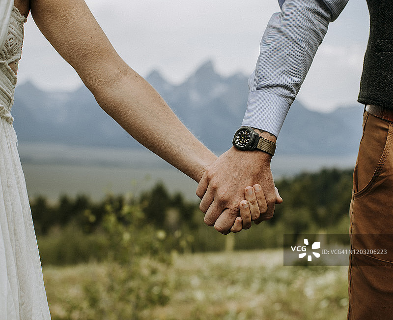 新娘和新郎在怀俄明州大提顿峰前手牵手图片素材