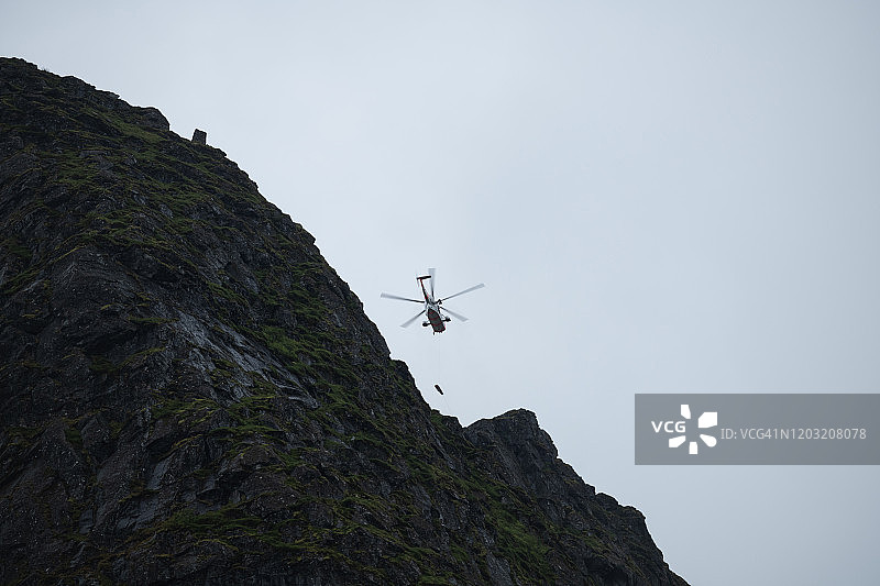 2019年8月21日：挪威海国王救援直升机在雷讷布林根山峰顶营救受伤的徒步旅行者，挪威罗弗敦群岛雷讷图片素材