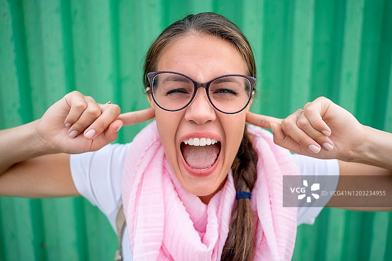 捂着耳朵尖叫的美丽女人肖像照片图片素材