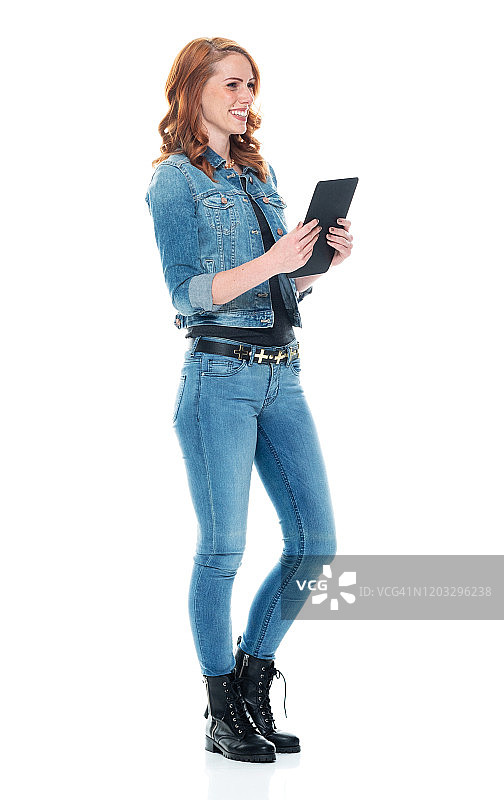 年轻白人女性站立，穿着牛仔裤，使用数位板图片素材
