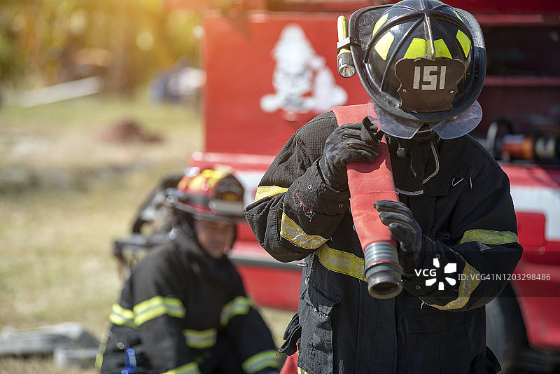 消防员身穿安全服走向冒烟的火灾区域，消防安全概念图片素材