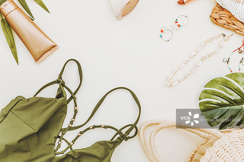 白色背景上的女性夏季比基尼泳装配饰拼贴，包括帽子、绿色树枝、项链和太阳镜。平铺，顶视图图片素材