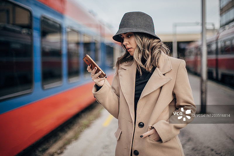 在火车站发短信的优雅年轻女子图片素材