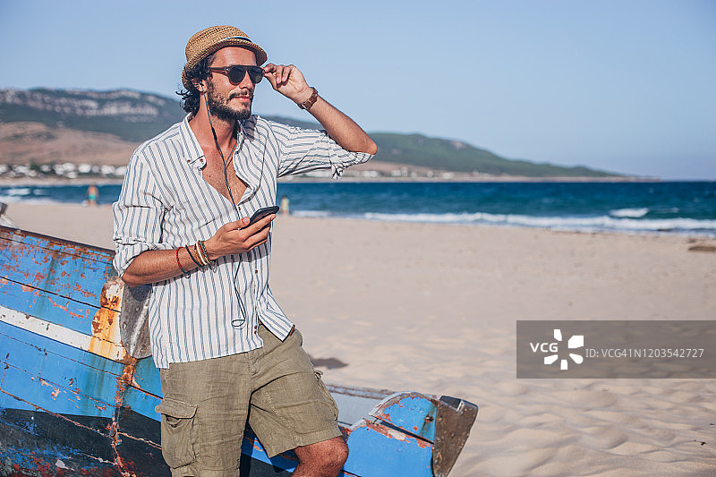 在海滩上听音乐的时尚男士图片素材