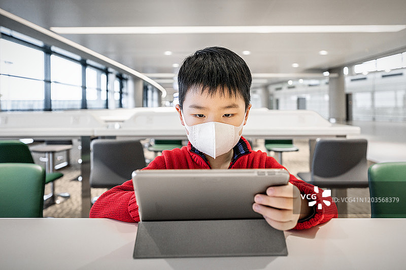 在机场戴口罩查看新型冠状病毒信息的男孩图片素材