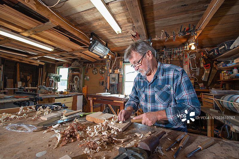 在工作室里做木工的年长木匠图片素材