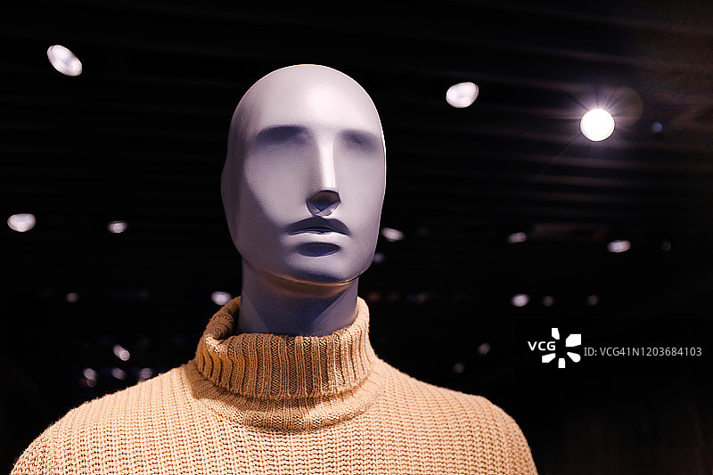 昂贵针织羊绒经典毛衣中的无脸人体模型，背景是闪烁的灯光图片素材