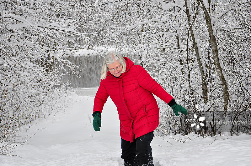 穿红夹克的年长女人在雪中行走图片素材