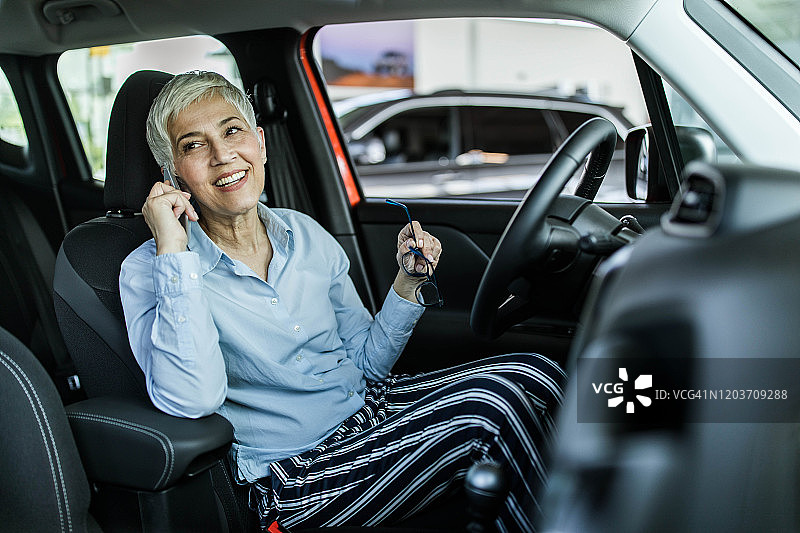 一位快乐的中年妇女在车内用手机交谈图片素材