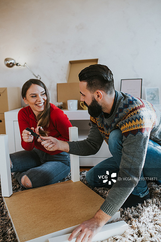 快乐的夫妇在客厅里组装家具，享受乐趣图片素材