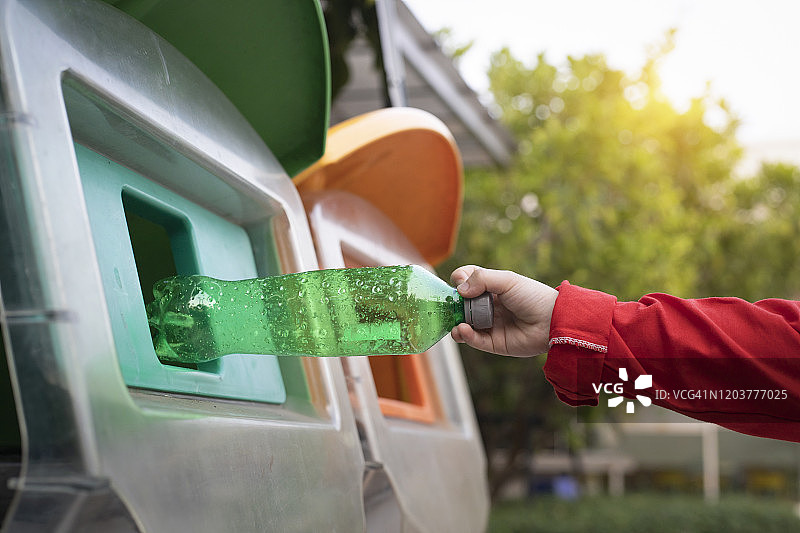 世界环境日概念：男孩的手拿着塑料瓶废品放入垃圾桶图片素材