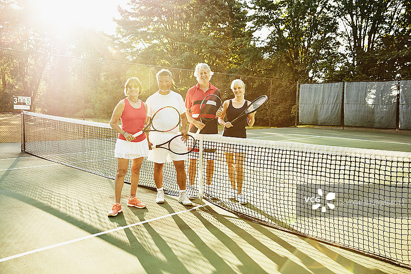 一群年长的朋友在清晨比赛前站在网球场上的微笑合影图片素材