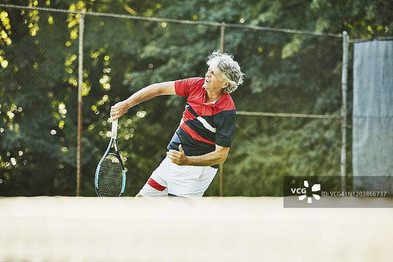 年长的男人网球运动员在网球比赛中猛击图片素材