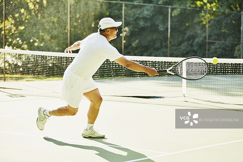 清晨网球比赛中回击球的年长男人图片素材
