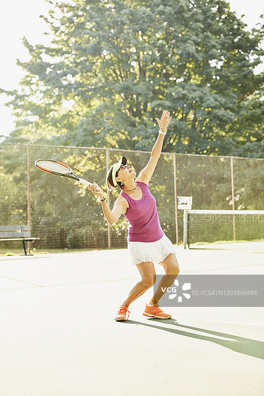 在清晨网球比赛中发球的年长女性图片素材