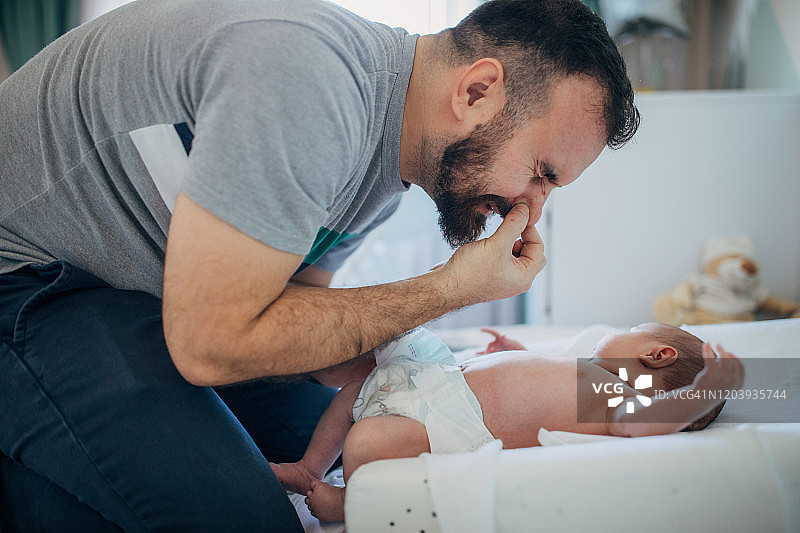 父亲在家给男婴换尿布图片素材
