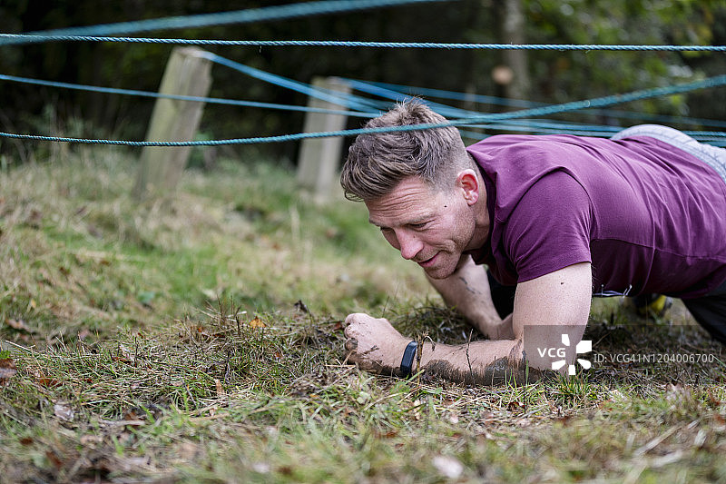 在泥泞户外障碍赛中手脚着地的健壮男人图片素材