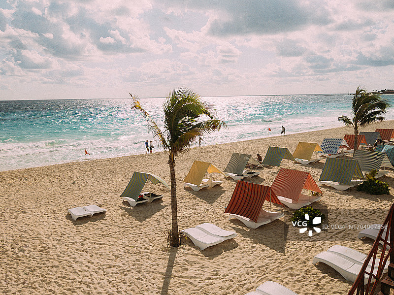阳光明媚的坎昆海滩，沙滩上有棕榈树和帐篷图片素材