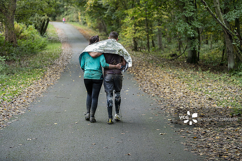 情侣分享锡箔毯，在乡间小路上行走图片素材