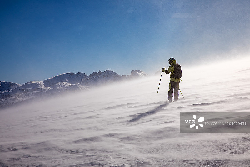 在美丽山脉前顶风行走的滑雪者图片素材