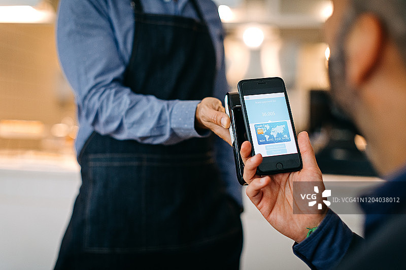 商人用智能手机在咖啡馆支付图片素材