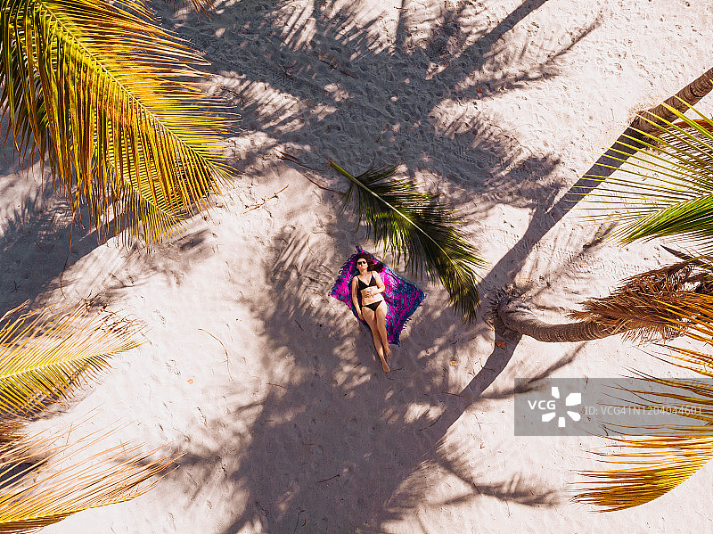 俯视：在椰子树下的基比斯坎海滩休息的女子图片素材